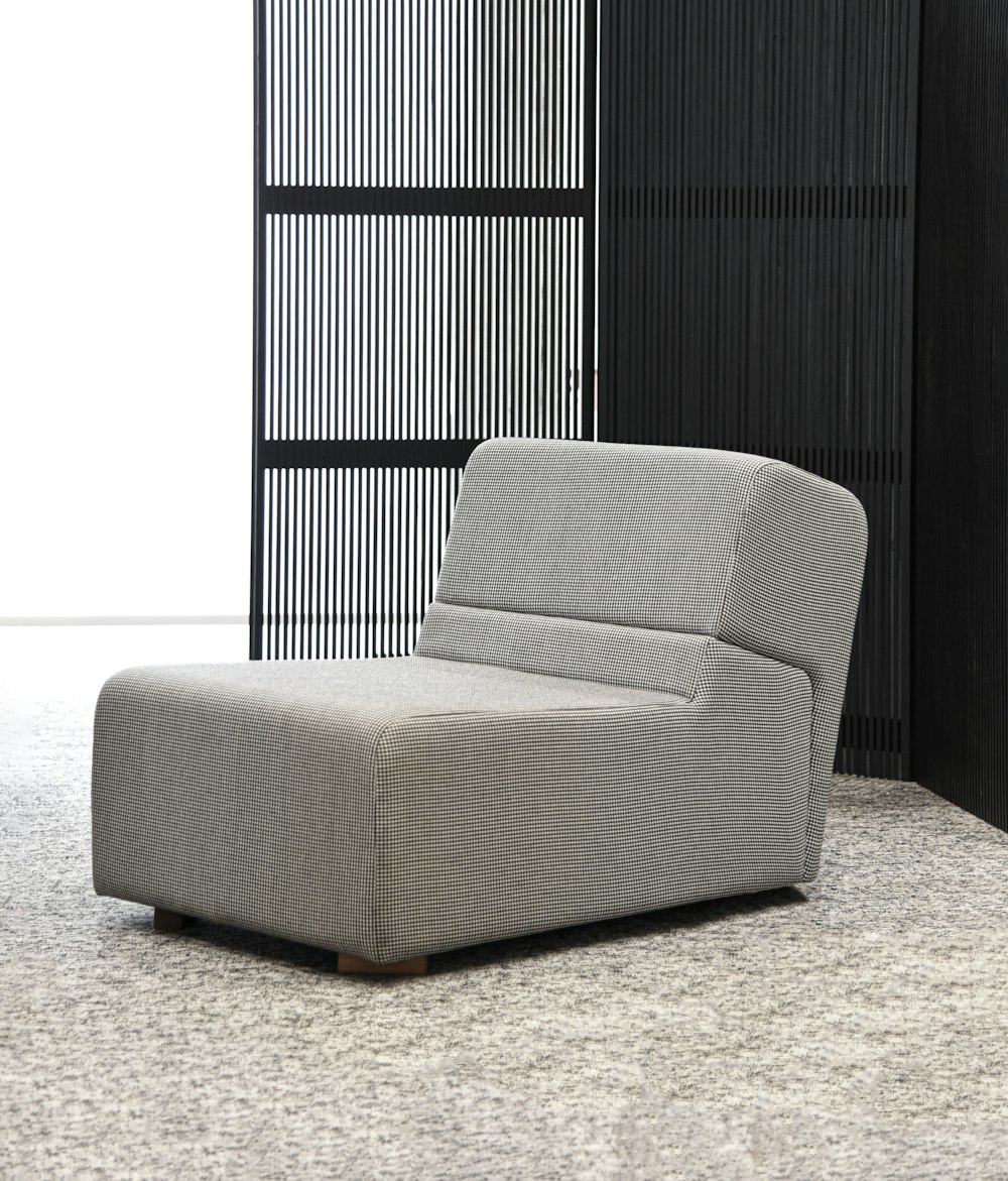 a gray chair sitting in front of a black wall