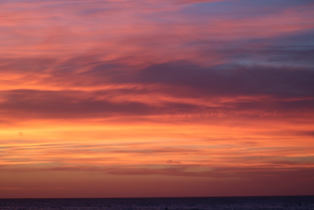 a red and blue sky at sunset over the ocean