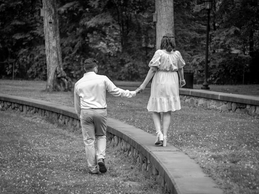 a man and a woman walking down a path holding hands