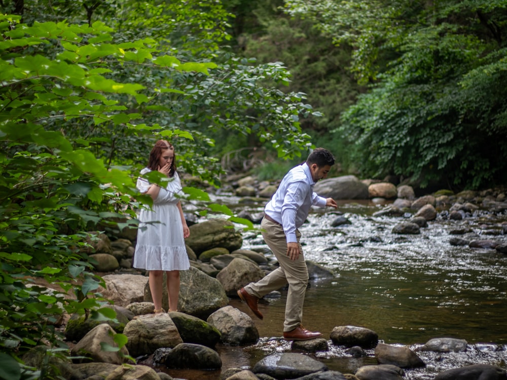 a man and a woman standing on rocks in a river