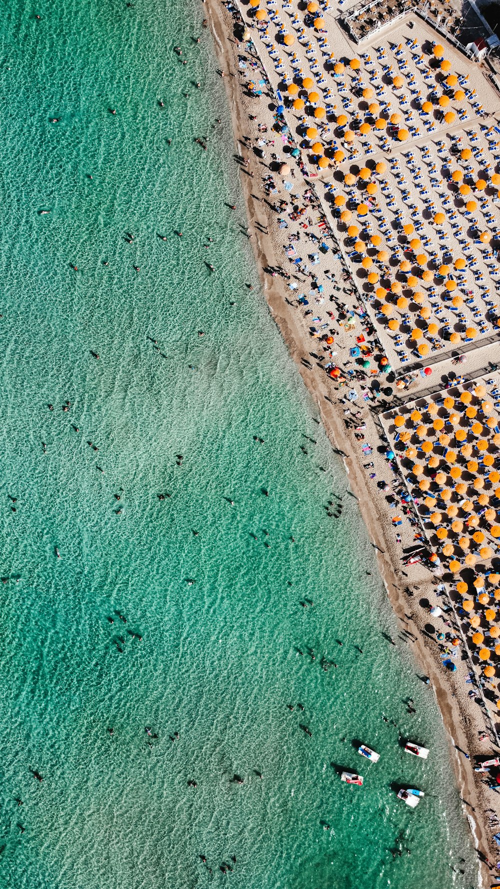 an aerial view of a beach with a lot of chairs and umbrellas