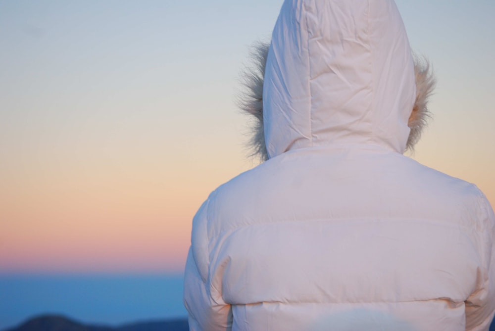 a person in a white jacket looking at the sky