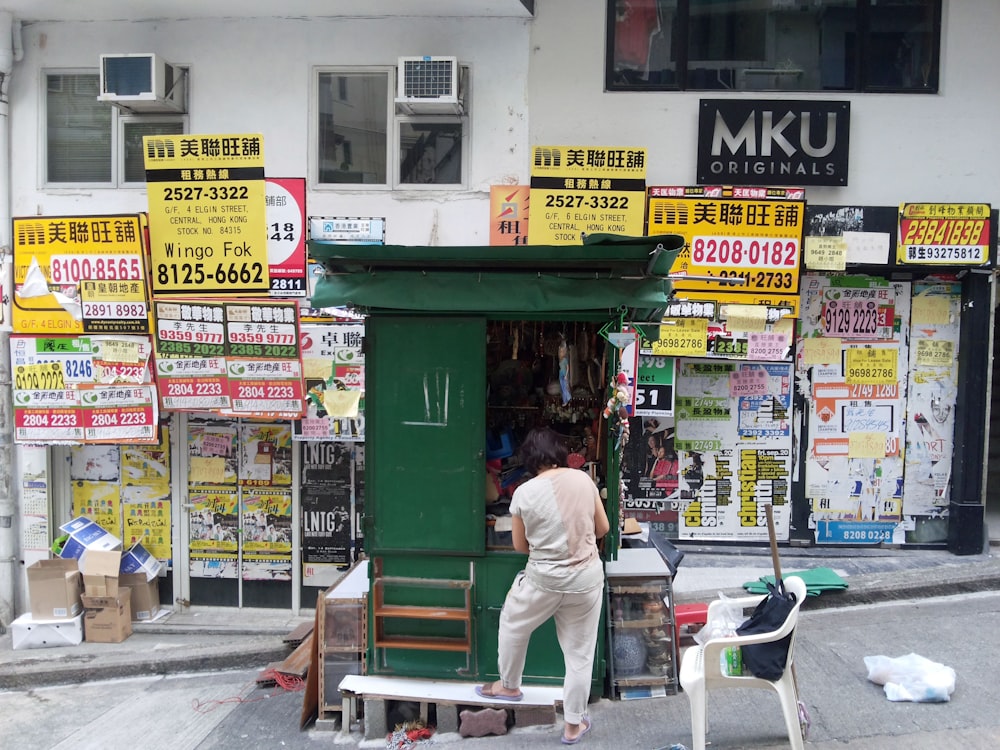 a man standing outside of a store with lots of signs