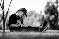 A relaxed person sitting outdoors with a notebook, jotting down financial goals.