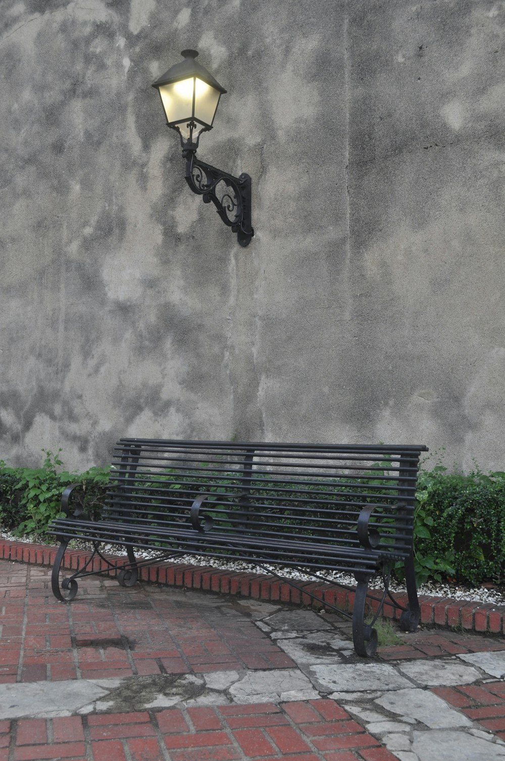 a bench and a street light against a concrete wall