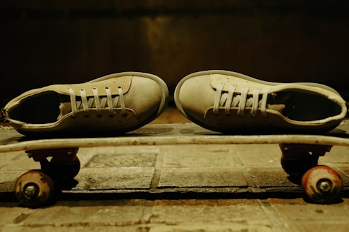Sneakers resting on a skateboard with graffiti walls in the background.