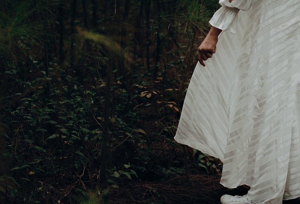 a woman in a white dress standing in a forest