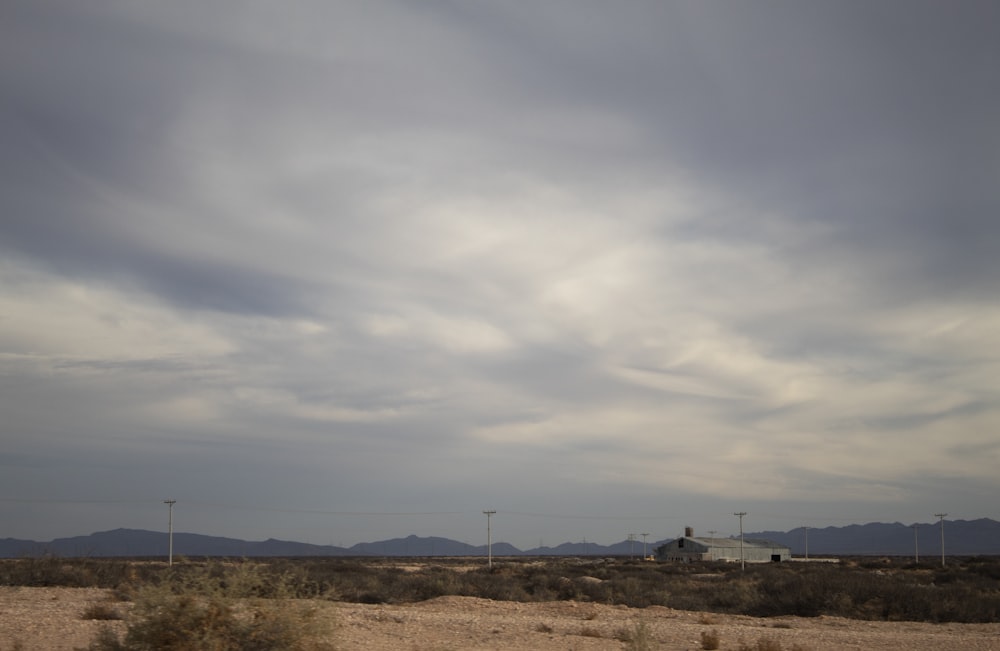 a cloudy sky over a desert landscape with mountains in the background