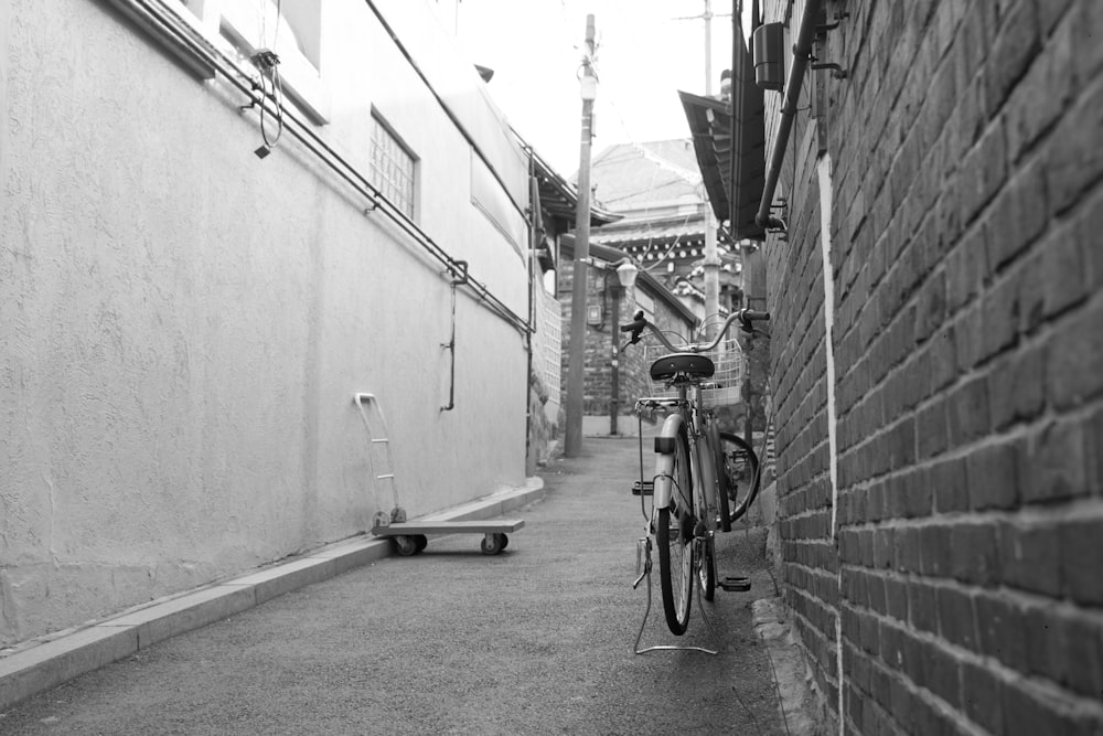 Una foto in bianco e nero di una bicicletta appoggiata a un muro