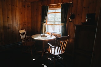 A cozy living room with sunlight streaming through windows, featuring a stack of financial books and a coffee cup on a wooden table.