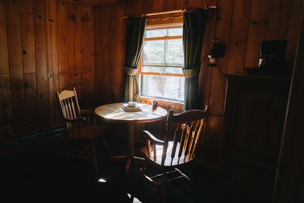 A cozy living room with sunlight streaming through windows, featuring a stack of financial books and a coffee cup on a wooden table.