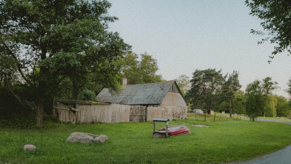 an old barn sits in the middle of a grassy field