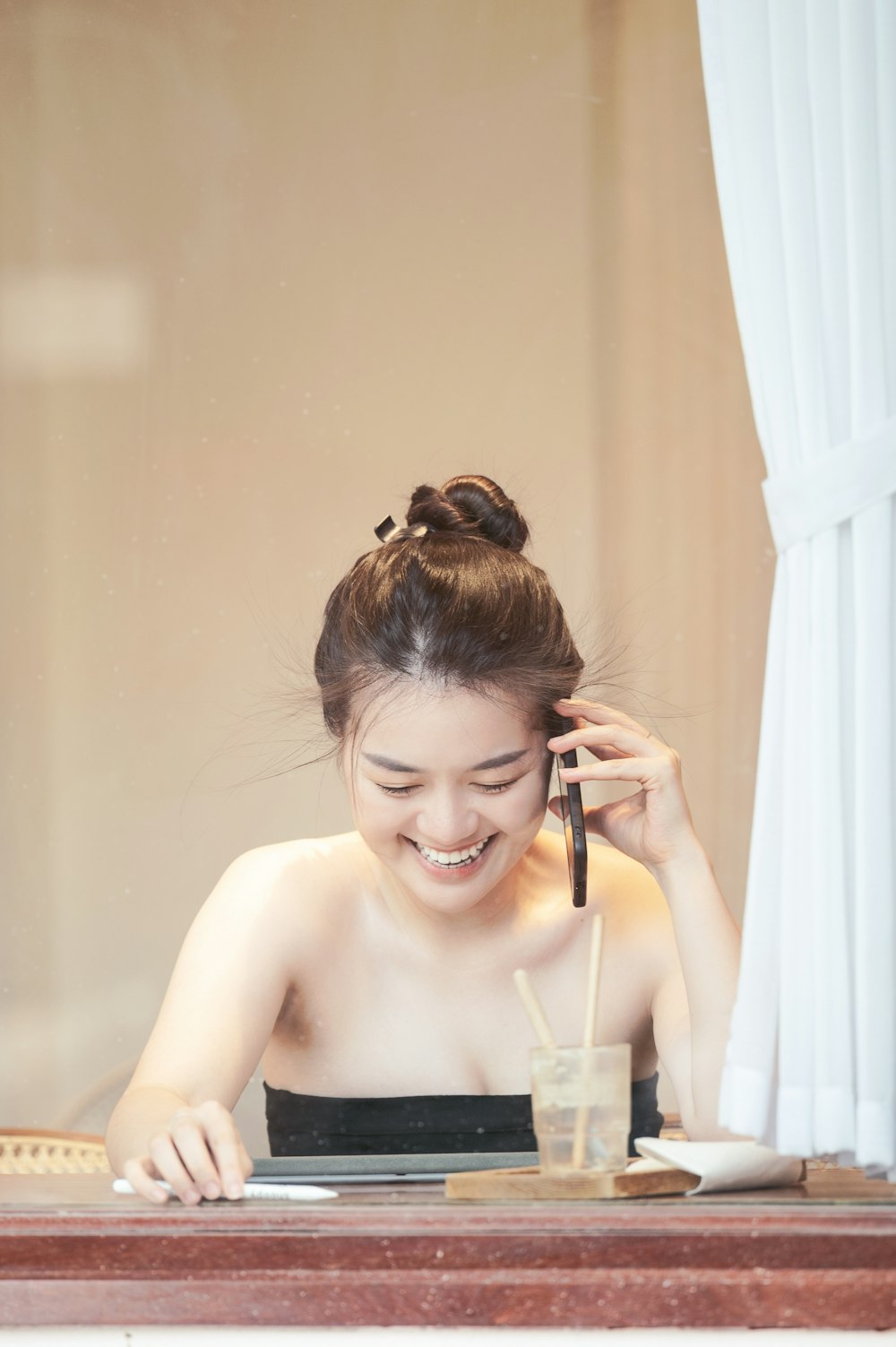 a woman sitting at a table talking on a cell phone