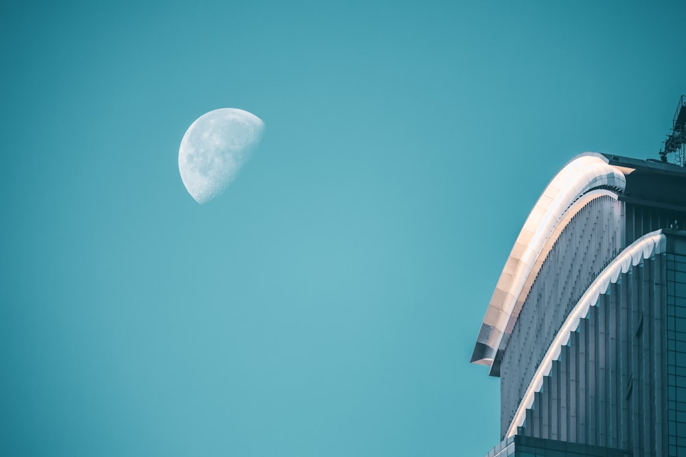 a very tall building with a half moon in the sky