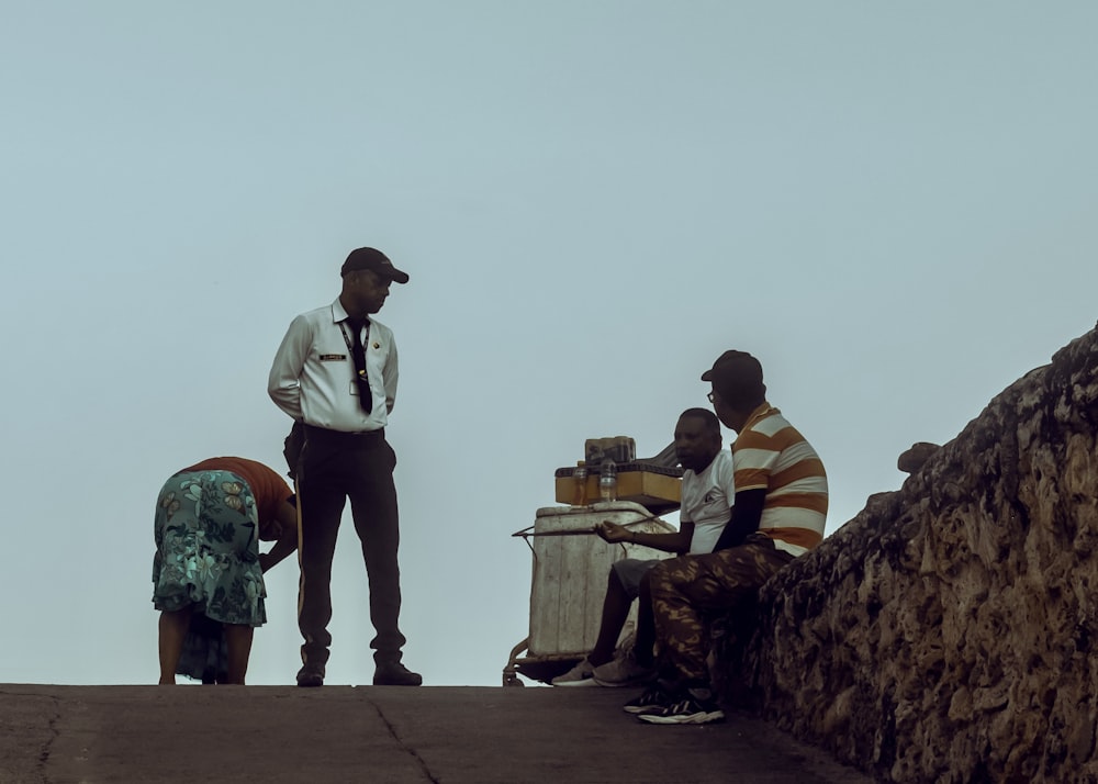 a group of men sitting on top of a stone wall