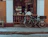 Smiling woman browsing bicycle accessories on a smartphone at a cozy café.