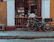 Smiling woman browsing bicycle accessories on a smartphone at a cozy café.