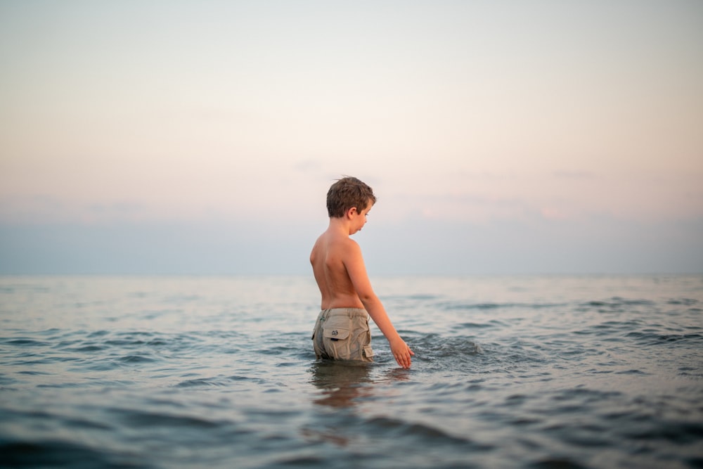 Un jeune garçon debout dans l’eau de l’océan