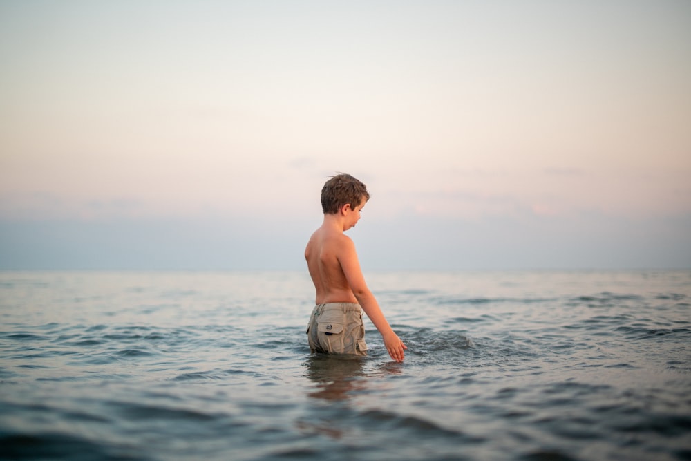 a young boy standing in the ocean water
