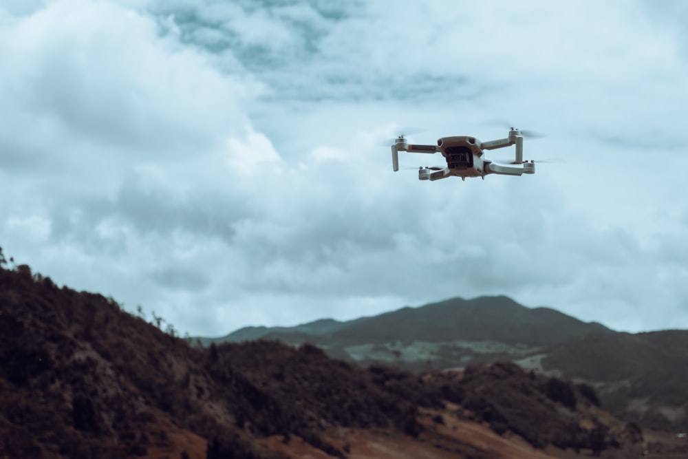 a white and black remote controlled flying over a mountain