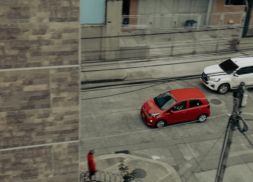 a red car driving down a street next to a white car