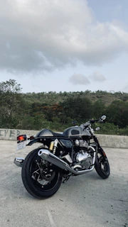 A shiny motorcycle parked beside a mountain trail under a clear blue sky.