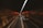 A dimly lit tunnel with a stream of cars traveling in a straight line. The tunnel walls reflect an orange glow from the overhead lights, creating a warm contrast against the darkness.