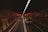 A dimly lit tunnel with a stream of cars traveling in a straight line. The tunnel walls reflect an orange glow from the overhead lights, creating a warm contrast against the darkness.