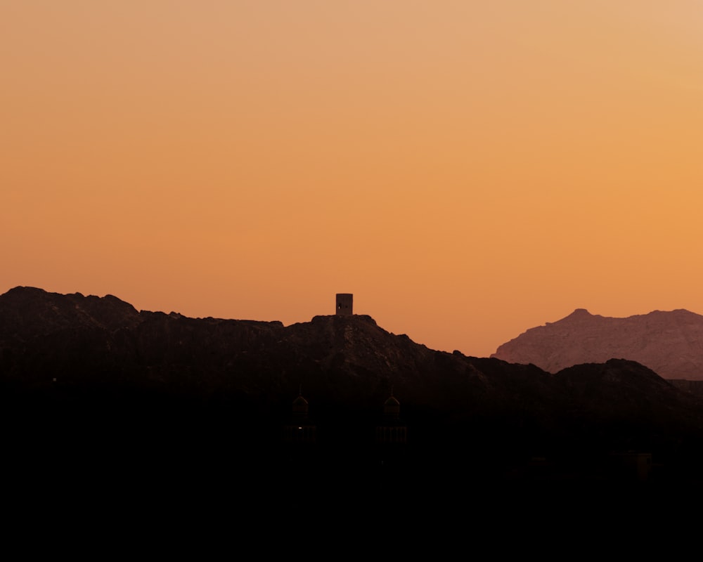 a silhouette of a mountain with a clock tower