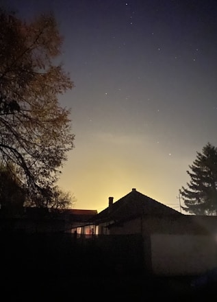 A cozy, stylish home silhouette glowing warmly against a twilight sky.