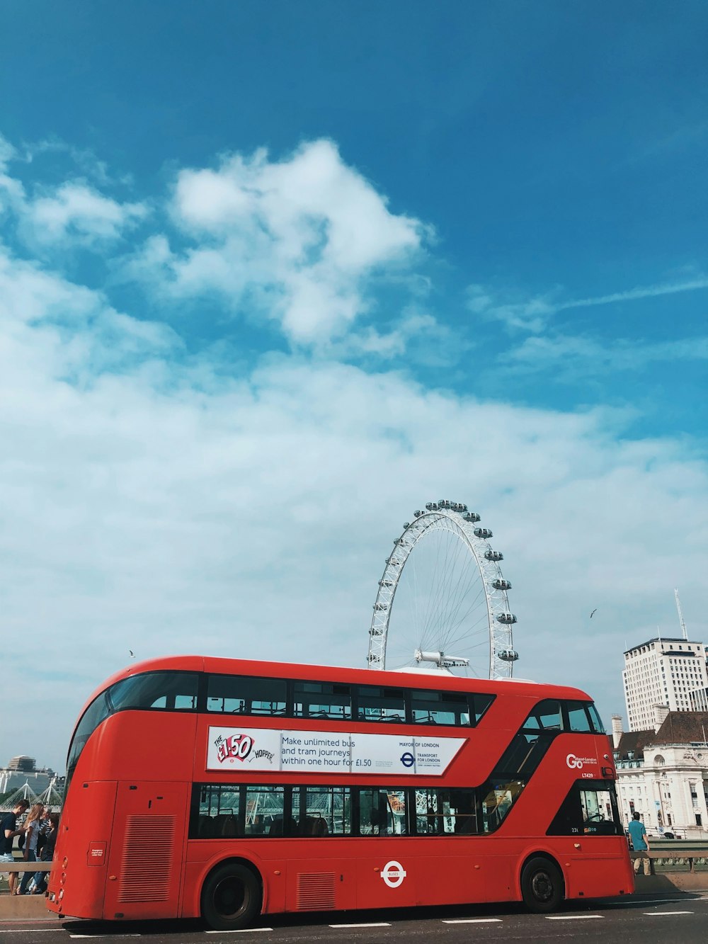 a red double decker bus parked in front of a ferris wheel