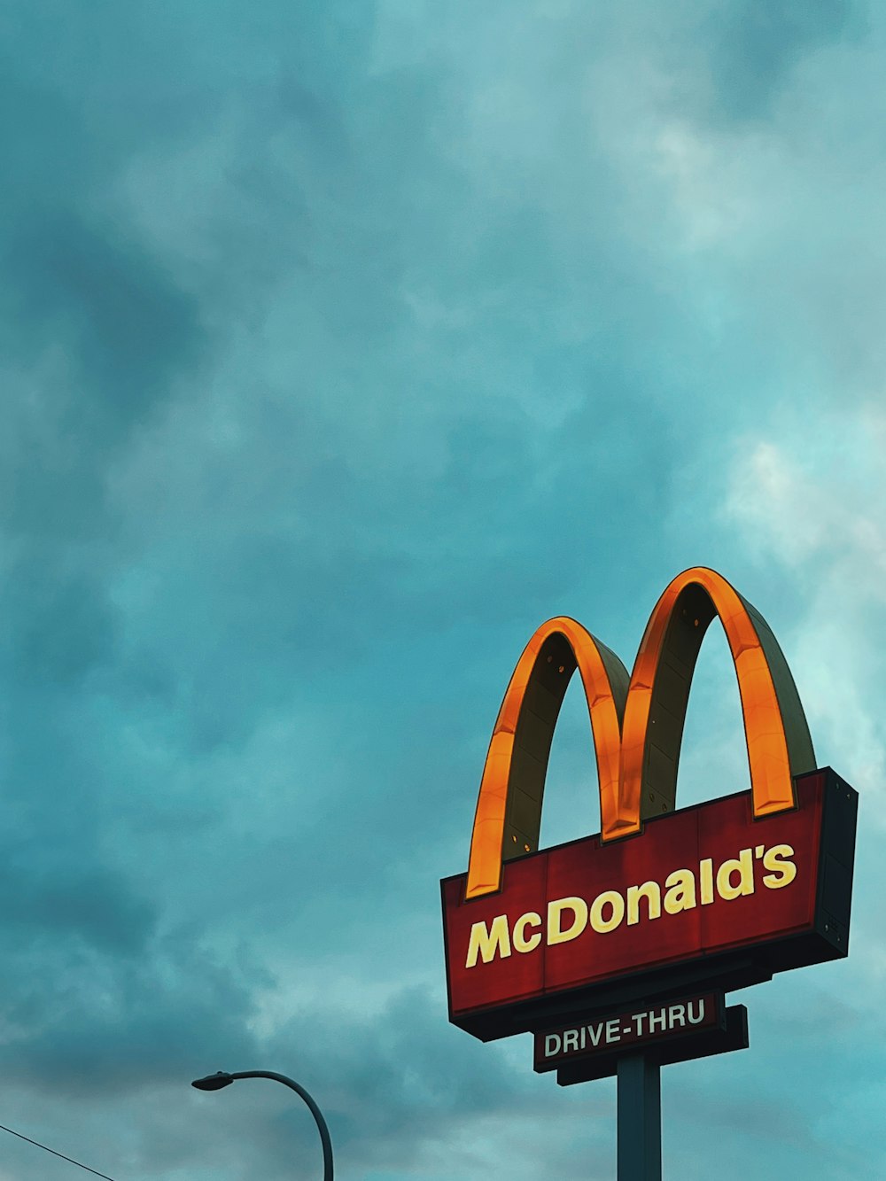 a mcdonald's drive thru sign under a cloudy sky