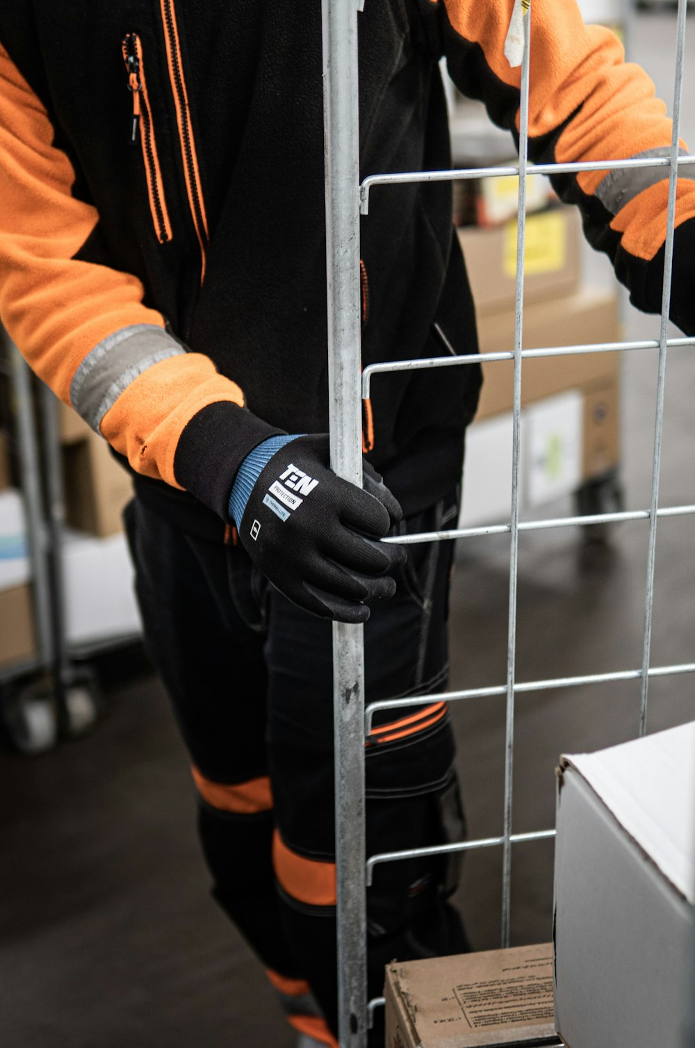a man in a black and orange jacket and gloves