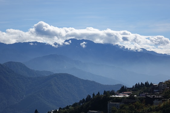 A panoramic view of Kabylie Village surrounded by lush green mountains under a clear blue sky.