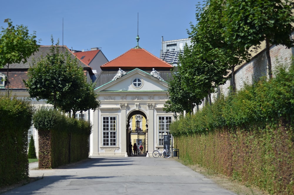 a white building with a red roof surrounded by hedges