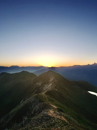 A breathtaking mountain trail winding through lush forests under a golden sunset sky.