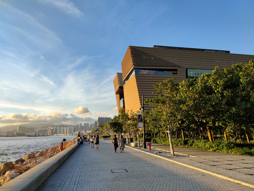 a group of people walking down a sidewalk next to a body of water