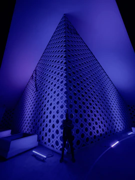 A sleek pyramid-shaped wellness pod glowing softly in a serene spa setting.