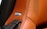 A close-up of a brown leather car seat or interior surface with detailed stitching. A BOSE metal emblem is embedded into the leather near some perforated holes, indicating a speaker system.
