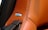 A close-up of a brown leather car seat or interior surface with detailed stitching. A BOSE metal emblem is embedded into the leather near some perforated holes, indicating a speaker system.