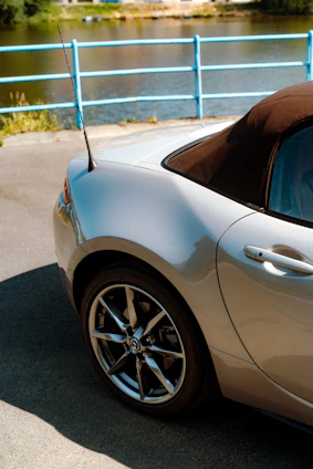 A shiny convertible cruising along a coastal highway under clear blue skies