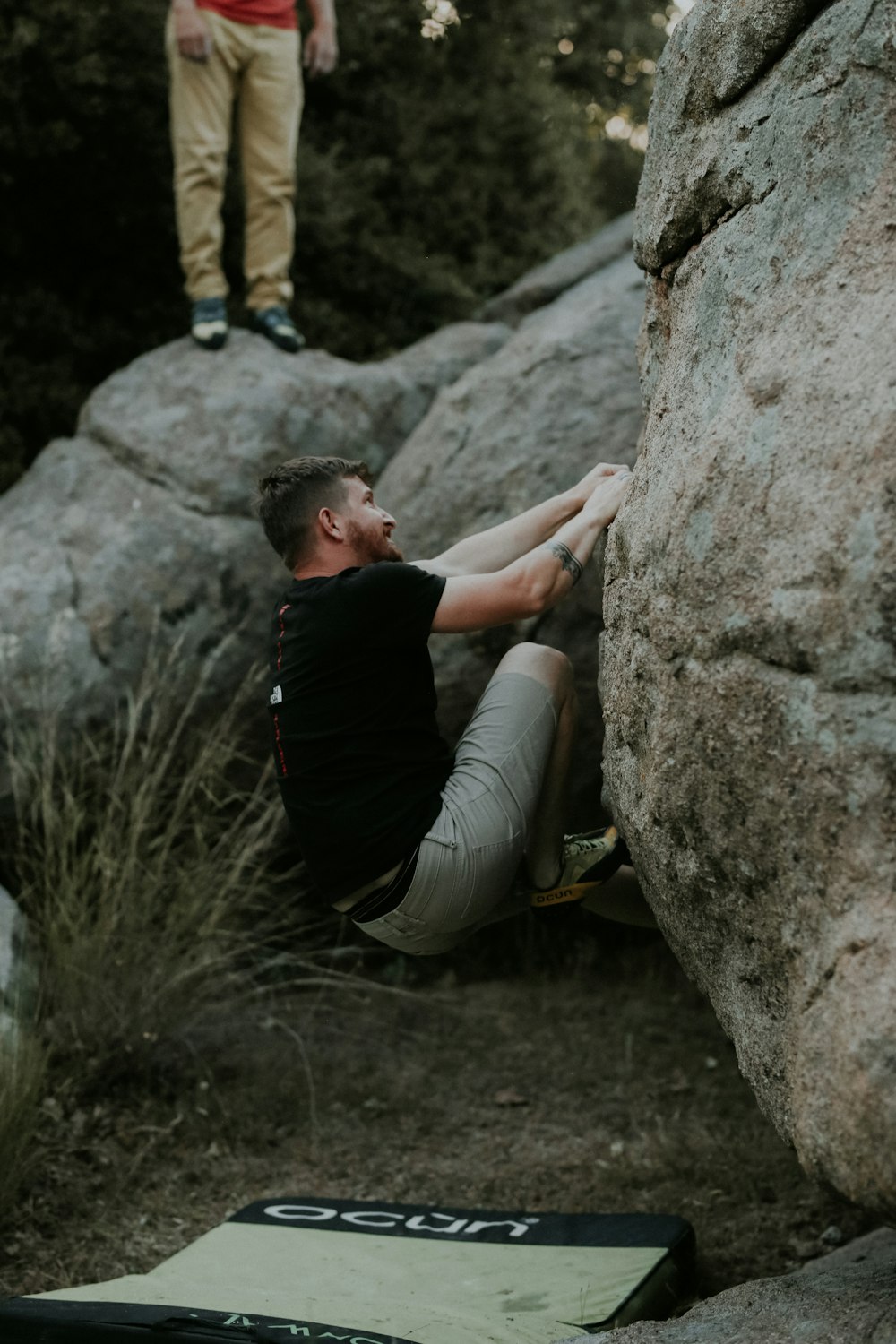 a man climbing up the side of a large rock