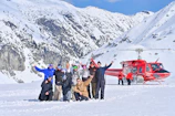 A group of happy pilgrims boarding a helicopter against a snowy mountain backdrop