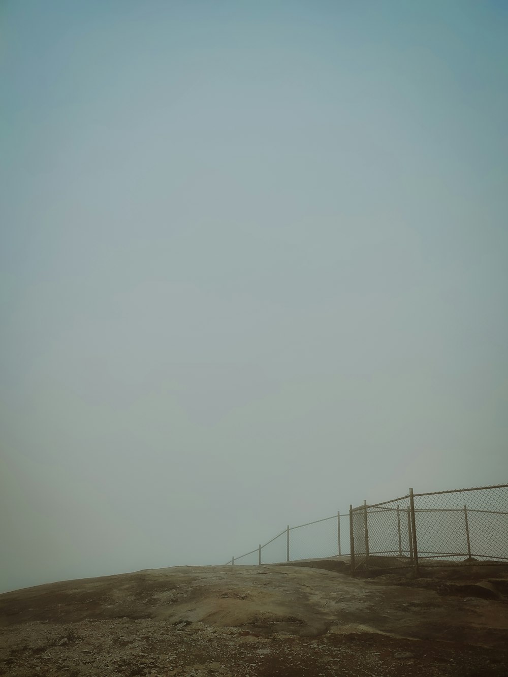 a dirt field with a fence and a sky background