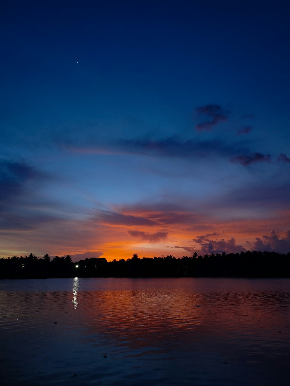 a sunset over a lake with a boat in the water