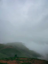 A serene view of the foggy landscape at Gorthan, showcasing lush greenery and mist-covered hills.
