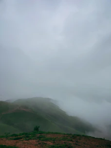 A serene view of the foggy landscape at Gorthan, showcasing lush greenery and mist-covered hills.