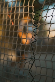 Close-up of a handwoven fishing net draped over a weathered wooden dock, sunlight filtering through.