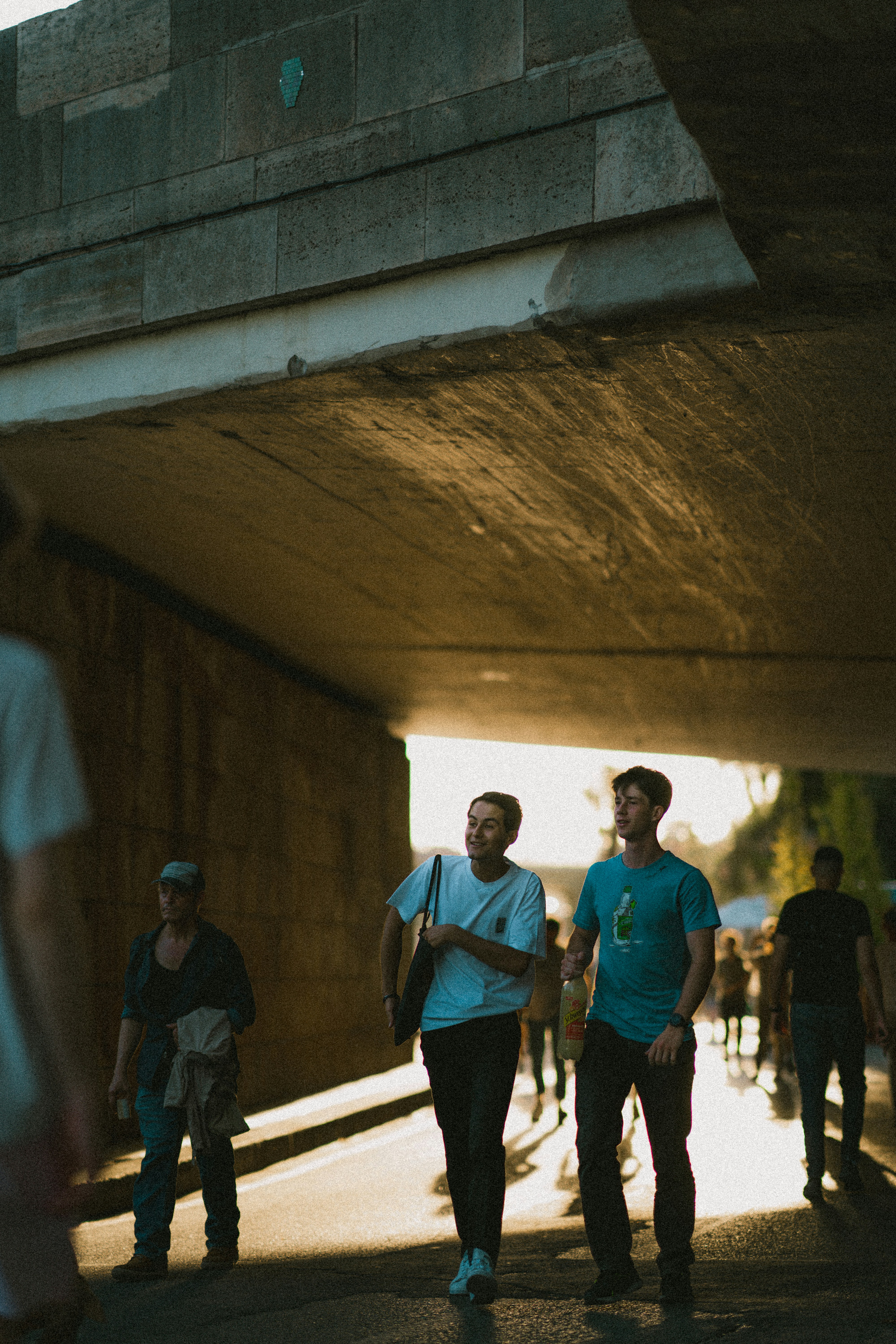a group of people walking under a bridge