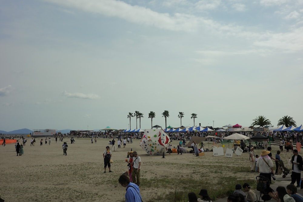 a crowd of people standing on top of a sandy beach